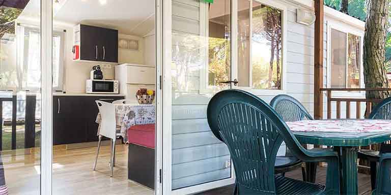 Spazioso maxi caravan con terrazza abitabile e attrezzata con tavolo e sedie con affaccio alla cucina.