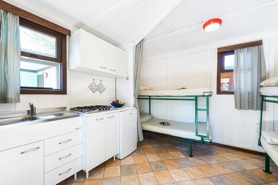 Interno del mini-bungalow con cucina e due letti a castello