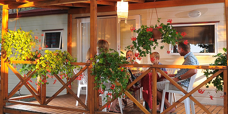 Terrazzo esterno coperto in legno del maxi caravan (casa mobile) arredato con tavolo e sedie