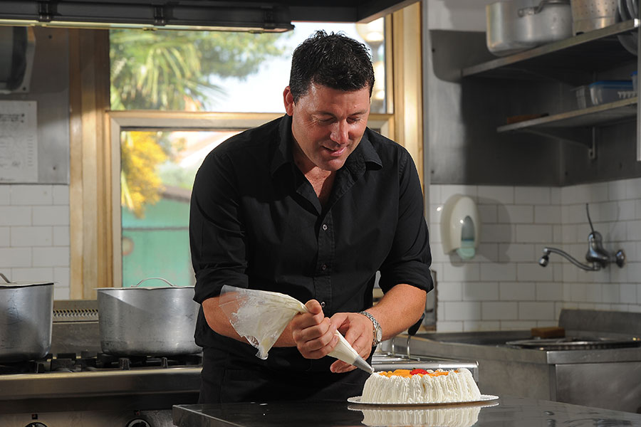 Cuoco in cucina che decora una torta