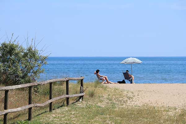 : Spiaggia e mare con pattino e ragazzi sdraiati a prendere il sole