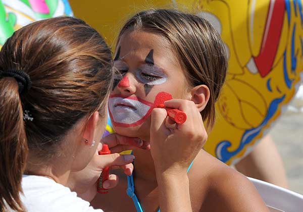 Una ragazza dell’animazione trucca il volto di una bambina